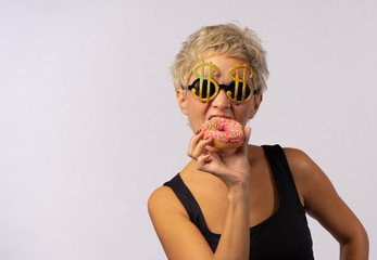 A beautiful mature woman is eating bright donut.
