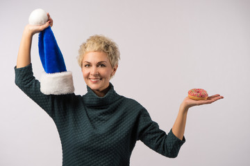 Beautiful mature woman is holding bright donut in hands.
