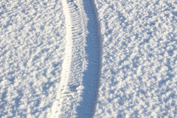 Tire tracks in the fresh snow. Wheel tracks on the road covered with snow. 
