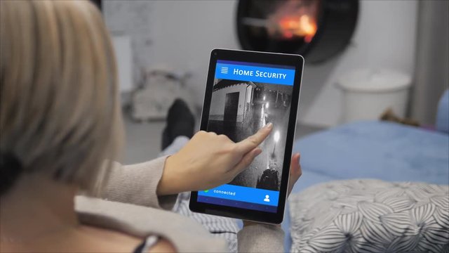 woman monitoring home video surveillance security camera on tablet app 4k