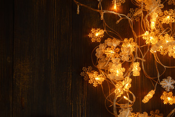 Christmas atmosphere flatlay on wooden background. Cookies, candies, electric garland and golden decorations