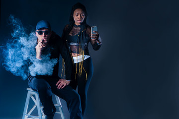 A man smokes an electronic cigarette. A man in the smoke. The guy and the girl smokes an electronic...