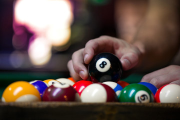 Sport billiard balls set arranged in shape of triangle on green billiard table in pub. Players are ready for the first hit of the round to start the billiard game.