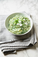 Spinach risotto with a glass of white wine on marble background