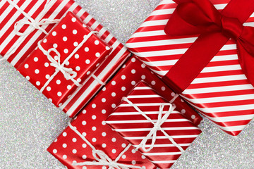 Various size wrapped in red paper with ornament Christmas gift boxes on shiny silver background