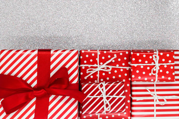 Various size wrapped in red paper with ornament Christmas gift boxes on shiny silver background