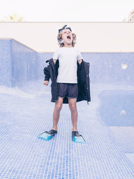 Boy in diving equipment and coat between empty pool