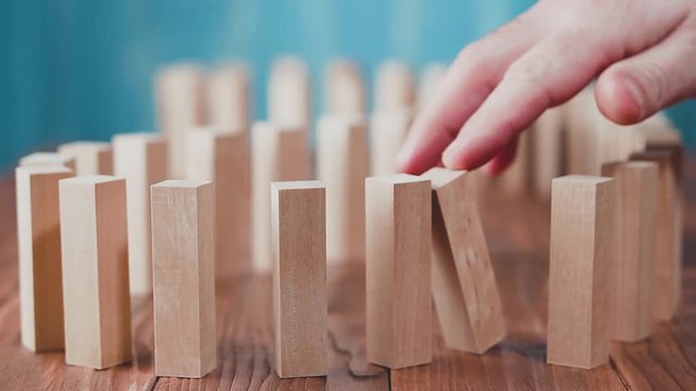 Domino effect. Wooden dominoes falling in sequences, chain reaction on a wooden table.