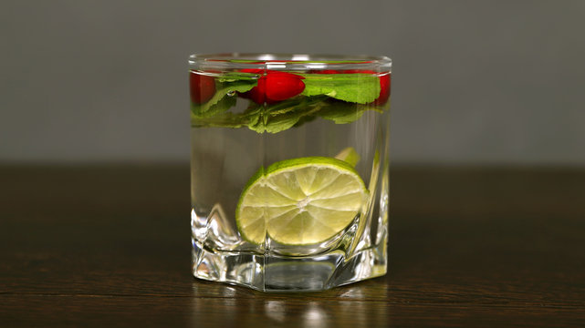 Напиток в стеклянном стакане с лимоном, лаймом и ягодами