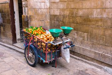 A cart by a Moroccan street fruit vendor equipped with scales for weighing fruits, filled with...