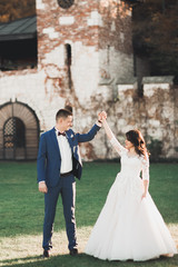 Lovely happy wedding couple, bride with long white dress posing in beautiful city