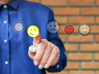 Business man in blue shirt is touching smiley face touch screen interface on customer satisfaction feedback concept