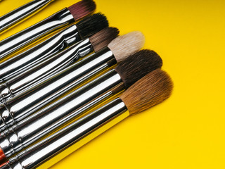 professional set makeup brushes on yellow background with copy space close up