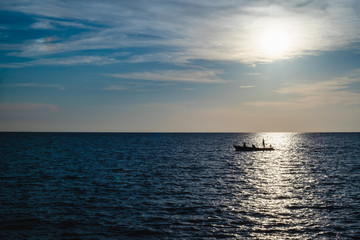 Silhouette of a fisherman on fishing boat with the sea and blue sky