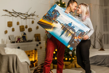 Happy young woman canvas and her boyfriend holding while moving into new home