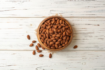 Almonds in bowl on white wooden background. Top view. Copy space.
