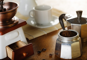 Making coffee. Coffee grinder, cup, light background