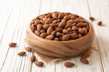 Almonds in bowl on white wooden background. Selective focus.