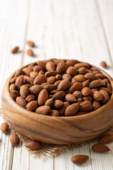 Almonds in bowl on white wooden background. Selective focus.