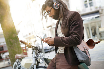 Hipster guy in town using headset with smartphone