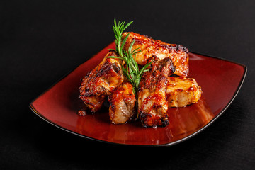 concept of American cuisine. Glazed pork ribs barbecue with rosemary on a red plate. Beautiful serving in the restaurant. background image