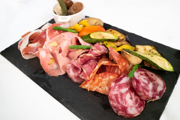 Assortment of tasty and delicious Italian Charcuterie antipasto delicatessen. Prosciutto di Parma or Parma ham, Salami sausage, Bologna, Chorizo and grilled vegetable. Perfect appetizer or party snack