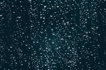 Naklejka na ściany i meble Dirty window glass with drops of rain. Atmospheric blue background with raindrops. Droplets and stains close up. Detailed transparent texture in macro with copy space. Rainy weather.