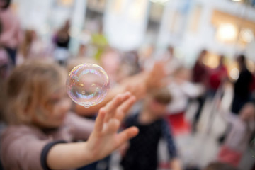 Curly girl catch a soap bubbles. Happy childhood concept.