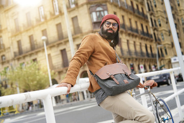 Hipster guy standing with bicycle in the street