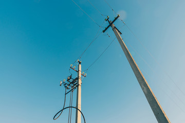 Power lines on background of blue sky close-up. Electric hub on pole. Electricity equipment with...