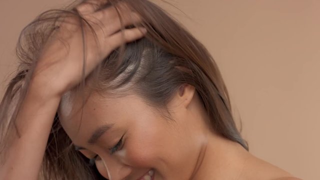 asian thai model smiling when hera hair blowing streaming in air cover her face. Natural smiling asian model in studio. 60fps slow motion