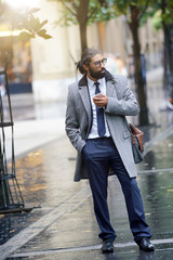 Businessman walking in the street, using smartphone