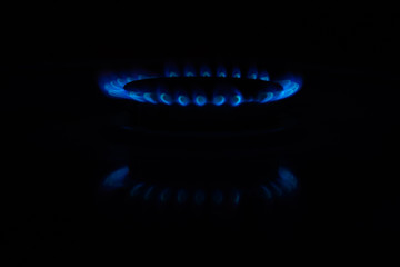 Circles of fire on a gas stove in the dark. Blue flame reflected on the surface