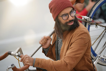 Hipster guy in town carrying fixie bicycle