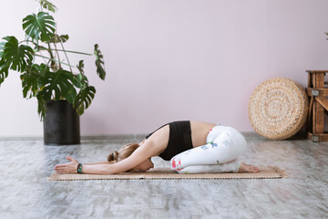 Beautiful girl in sportswear doing yoga Child's Resting Pose or Balasana on yoga mat