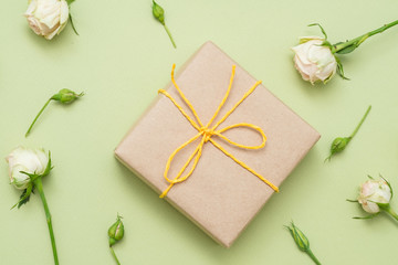 gift box and scattered roses layout on light green background