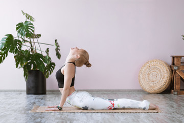 Beautiful adult fitness woman in sportswear working out in studio, doing yoga cobra pose or...