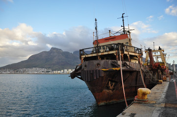 Old rusty ship on the pier of Cape Town against the background of the city and mountains