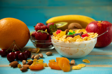 Tasty cornflakes with milk and fruits in glass bowl