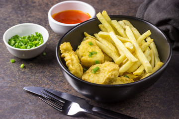 plate of chicken nuggets with french fries on dark background, junk food and unhealthy food, selective focus