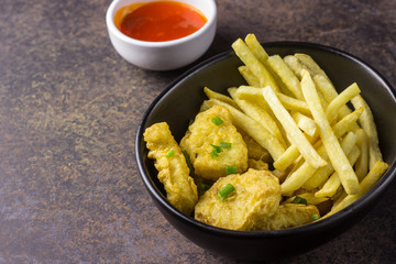 plate of chicken nuggets with french fries on dark background, junk food and unhealthy food, selective focus
