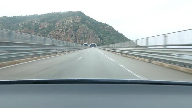 Approaching and driving into tunnel on the E90 in Sicily, Italy. Dramatic cliff face.