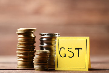 Inscription GST on paper with stack of coins