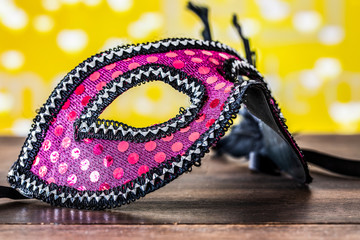 Pink mask on a wooden table. Carnival background.