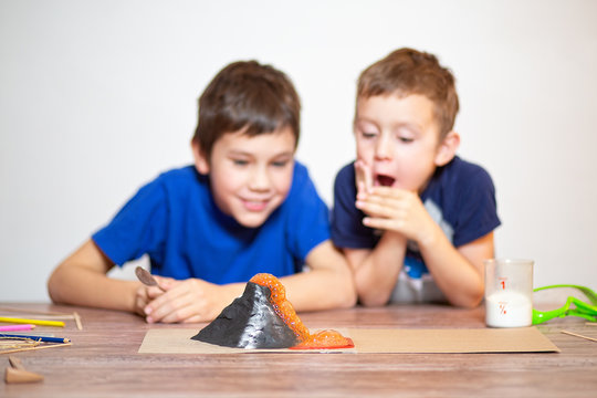 Two boys watching a chemistry experiment. volcanic eruption. school science project. children surprised. Chemical reaction of baking soda and vinegar. Selective focus