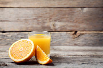 Orange fruit with glass of juice on grey wooden table