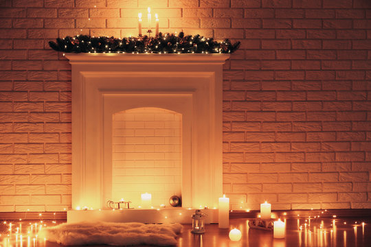 White decorated fireplace with candles on brick wall background