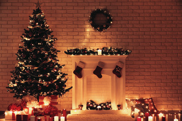 White decorated fireplace near christmas tree on brick wall background