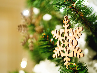 Christmas and New Year rustic decorations - wooden snowflakes on Christmas tree with light bulbs.