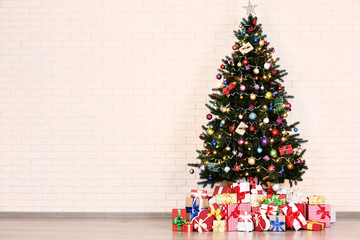 Christmas tree with decorations and gift boxes on brick wall background